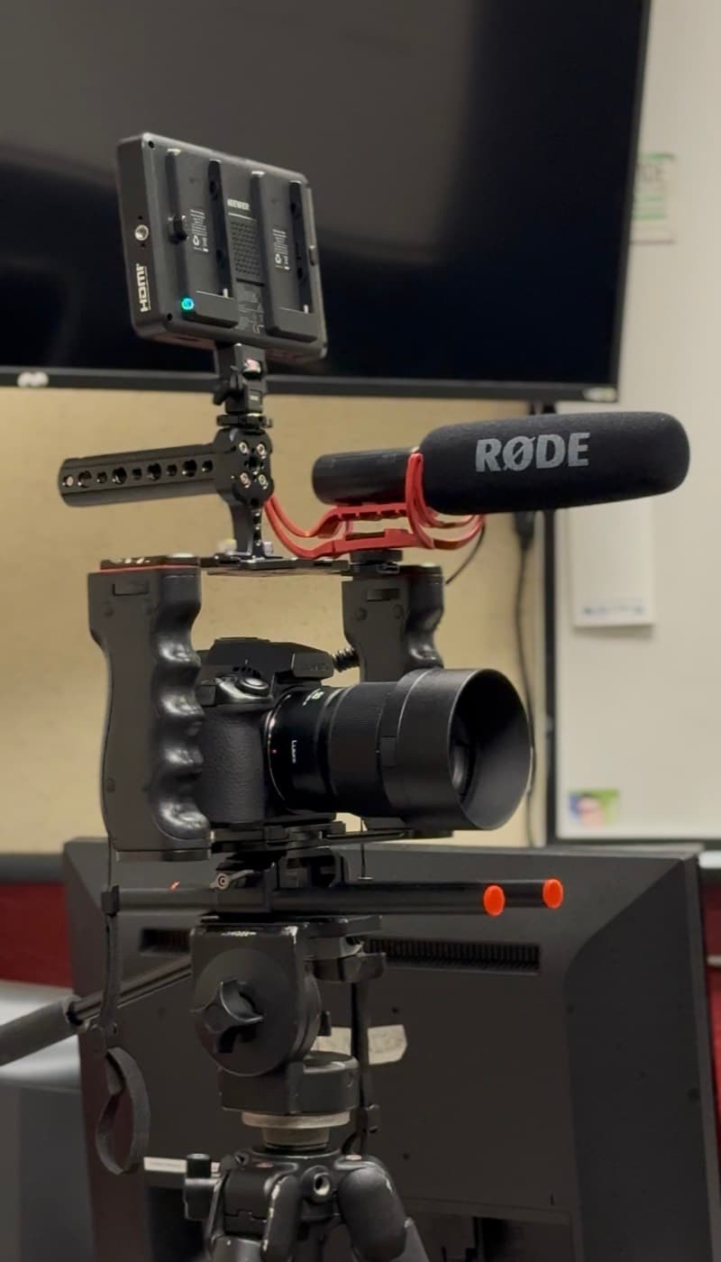 A rigged cinema camera with a shotgun microphone and field monitor in the DMI lab